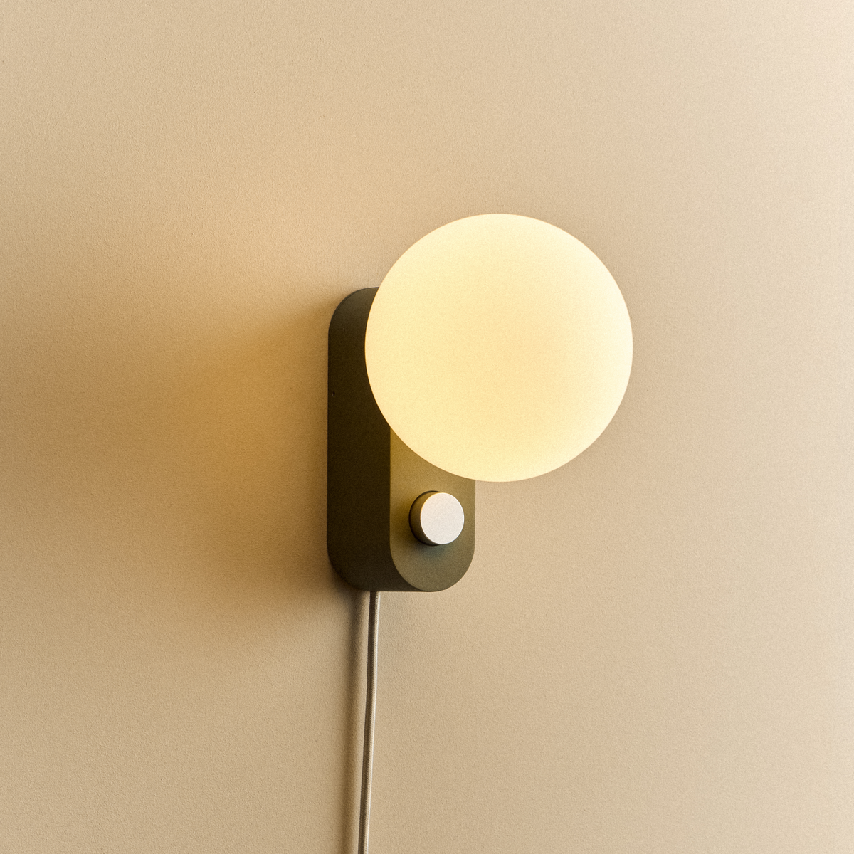 Alumina Lamp in Sage mounted on a wall, lit
