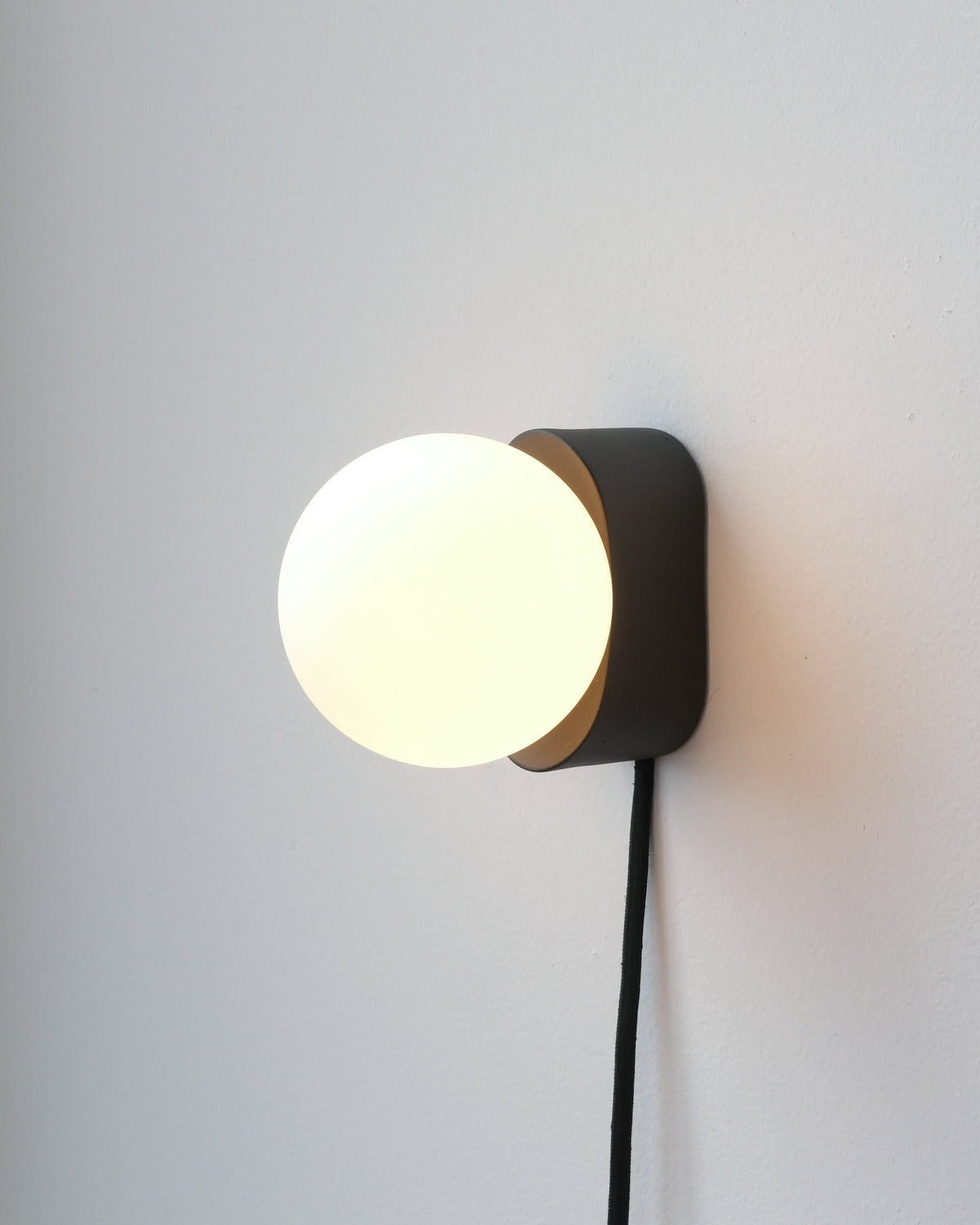 Iota Sconce in Black with its plug-in cord