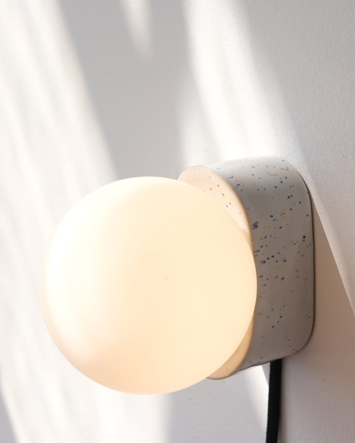 Iota Sconce in Speckle, lit