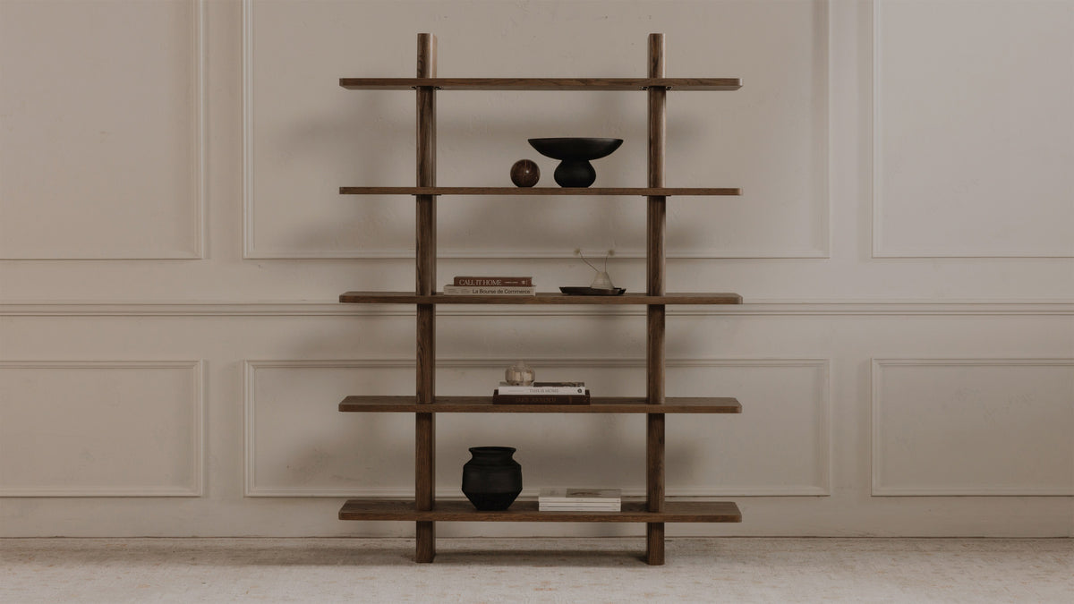Moe's Home Collection Casey Large bookcase in dark brown oak, four shelves stepping between two solid uprights, holding books and a small black bowl against a panelled wall