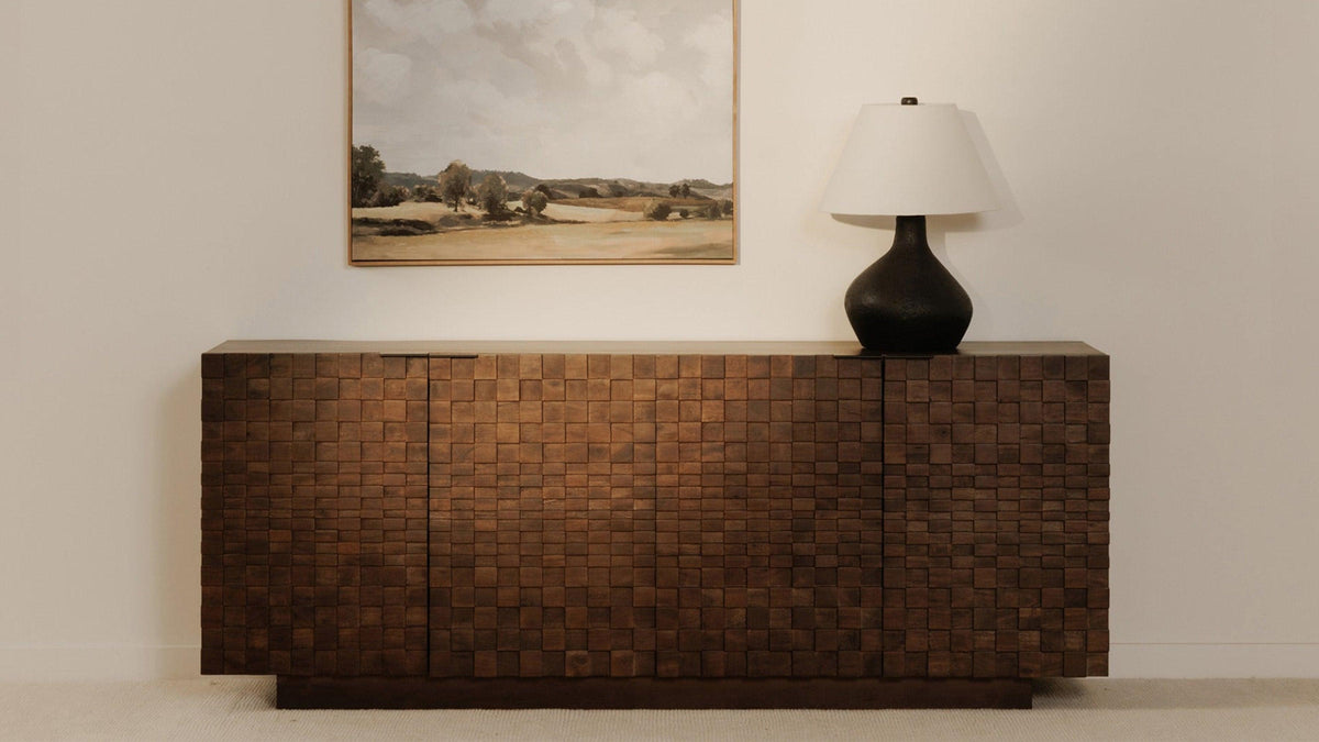 Moe's Home Collection Easton sideboard in brown acacia, its checkerboard door fronts in raised relief, with a table lamp on one end and a framed desert landscape hanging above
