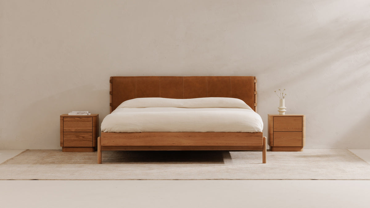 A pair of Moe's Home Collection Round Off Tall nightstands in light oak flanking an oak bed with a tan leather headboard, each a two-drawer case with softened corners sitting on a recessed plinth