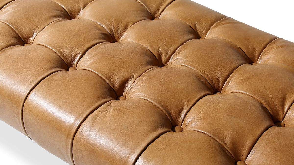 Close view of the Wyatt bench's tan top-grain leather seat, showing the grid of deep square tufting across the cushion