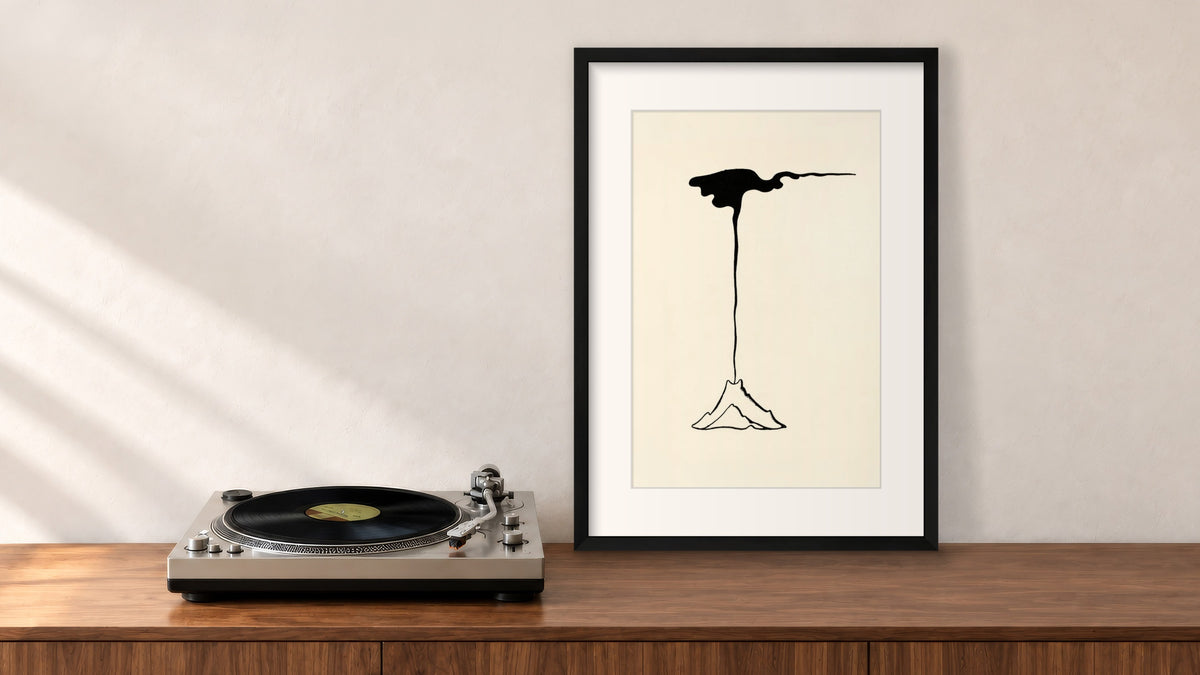 Volcano in Eruption Framed Print in a black frame, leaning on a walnut console beside a turntable