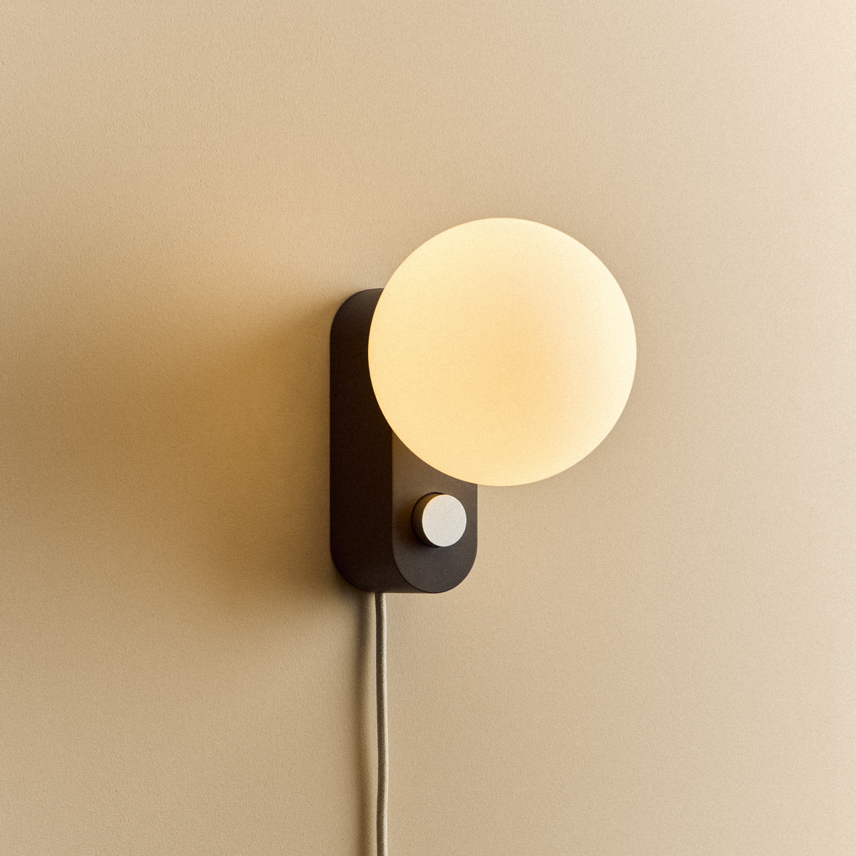 Alumina Lamp in Charcoal mounted on a wall, lit