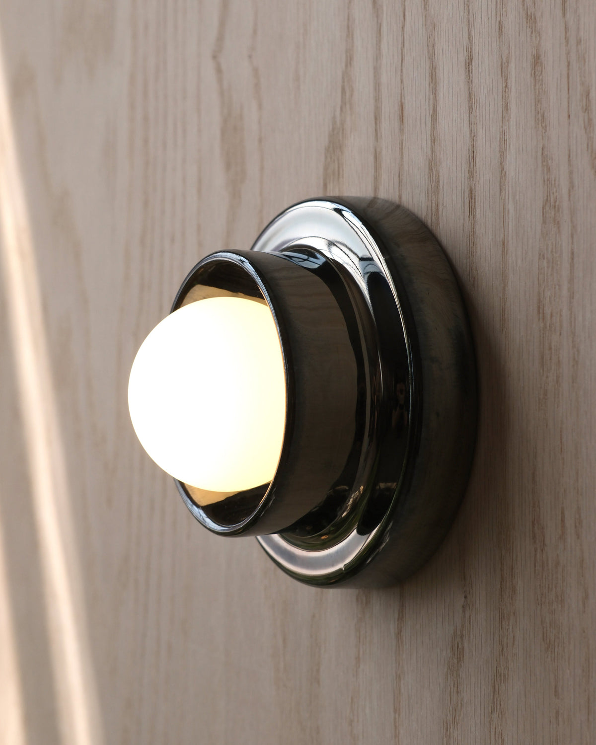 Q Sconce in Chrome on a wood wall