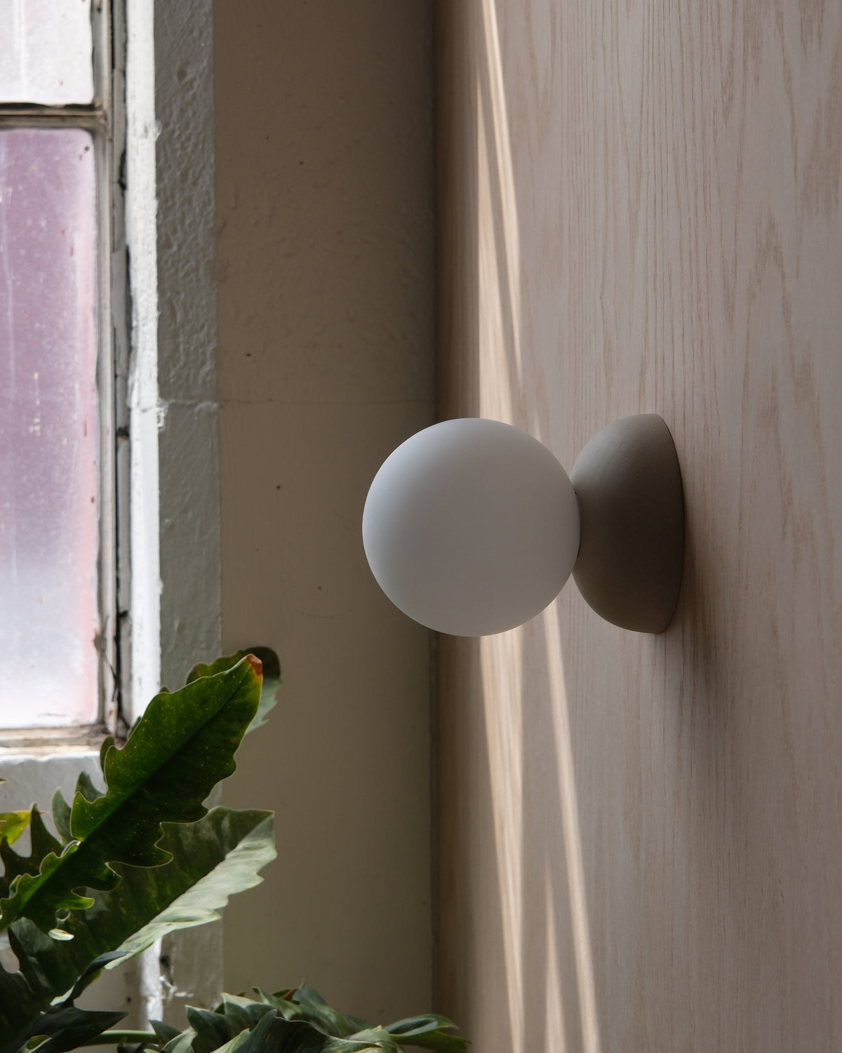 Monroe Sconce in White Matte beside a window