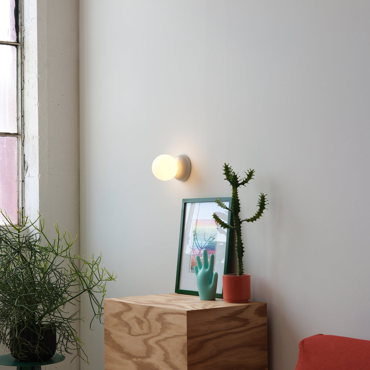 Monroe Sconce, lit, above a plywood cabinet