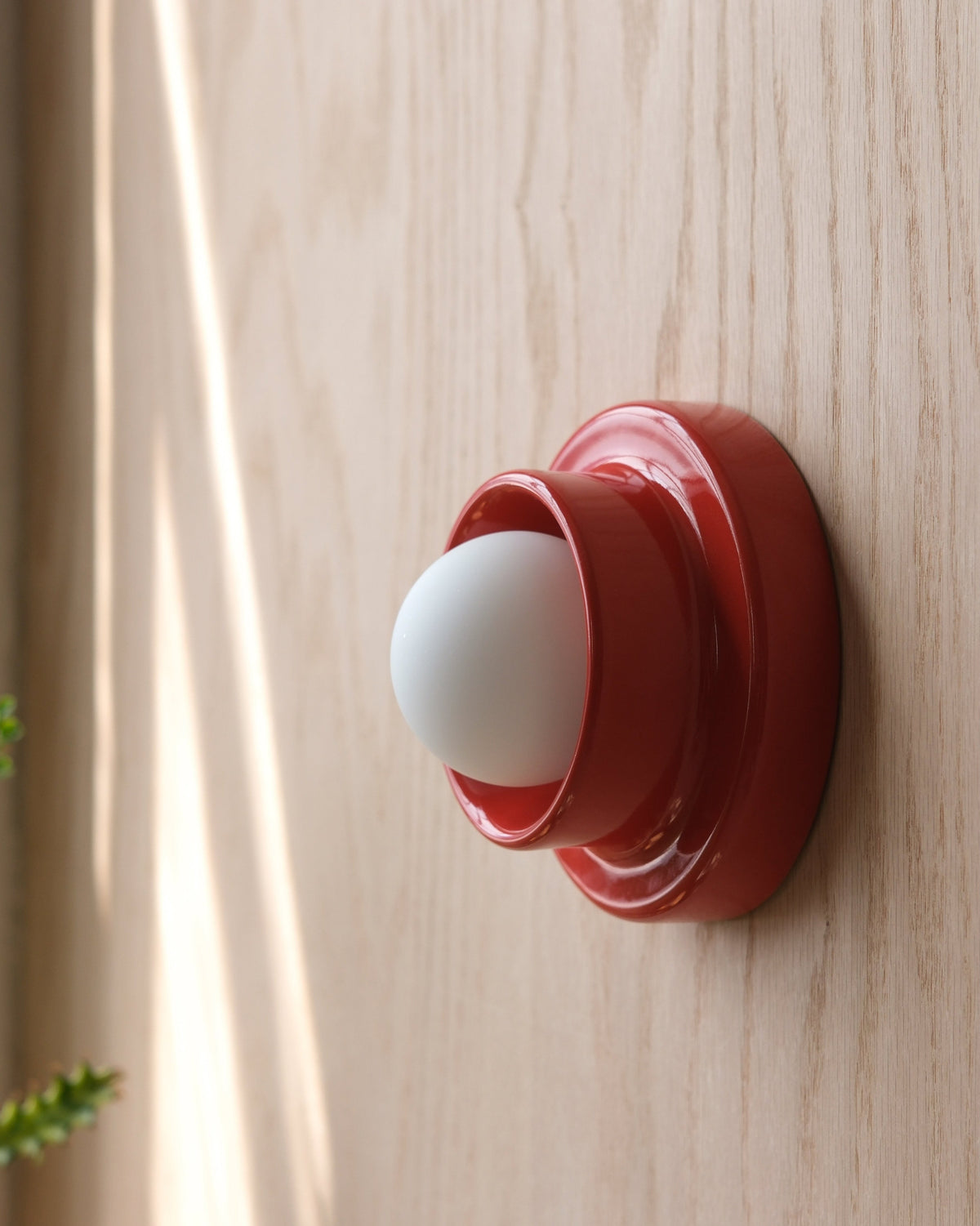 Q Sconce in Red on a wood wall