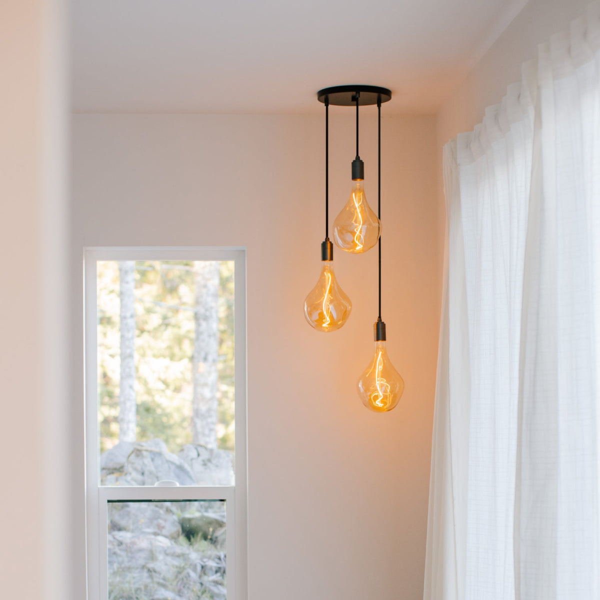 Voronoi II Triple Pendant in Graphite, switched on, in a room with sheer curtains