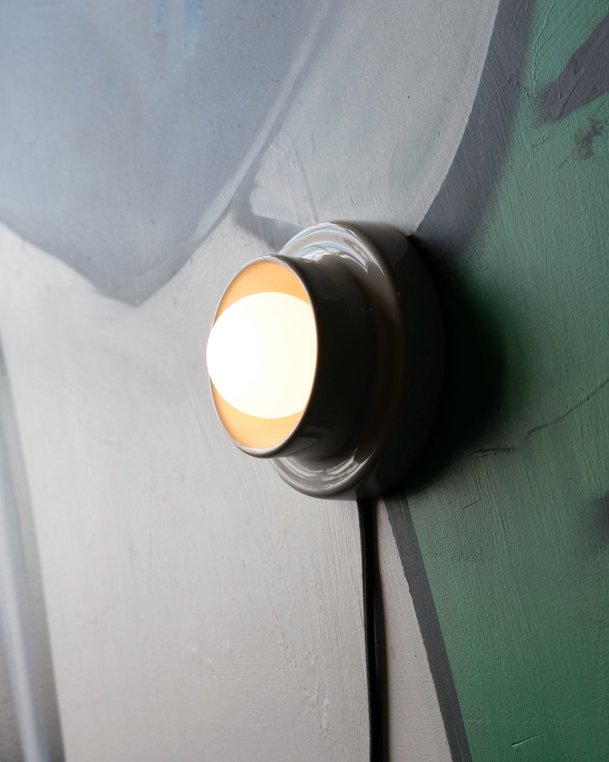Q Sconce, lit, on a painted mural