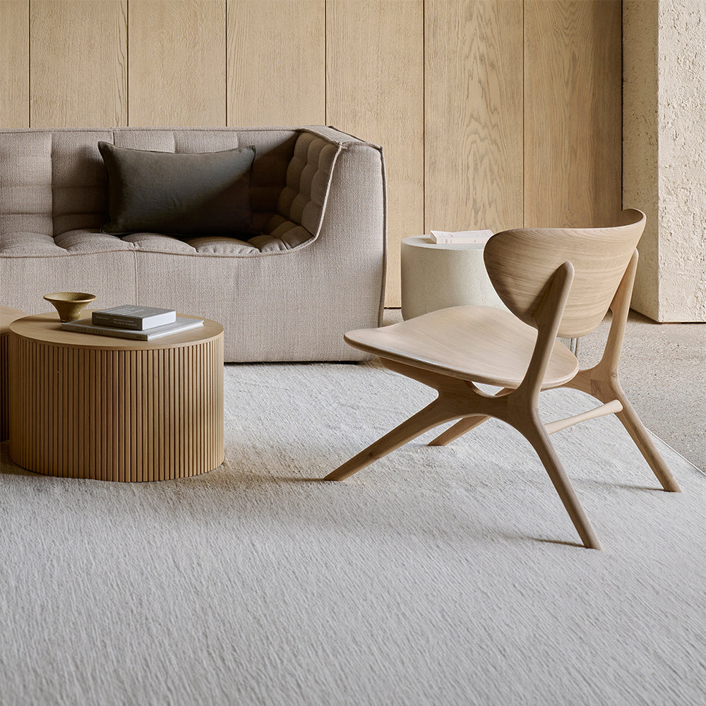 Modern living room with a beige sofa, wooden chair, and coffee table.