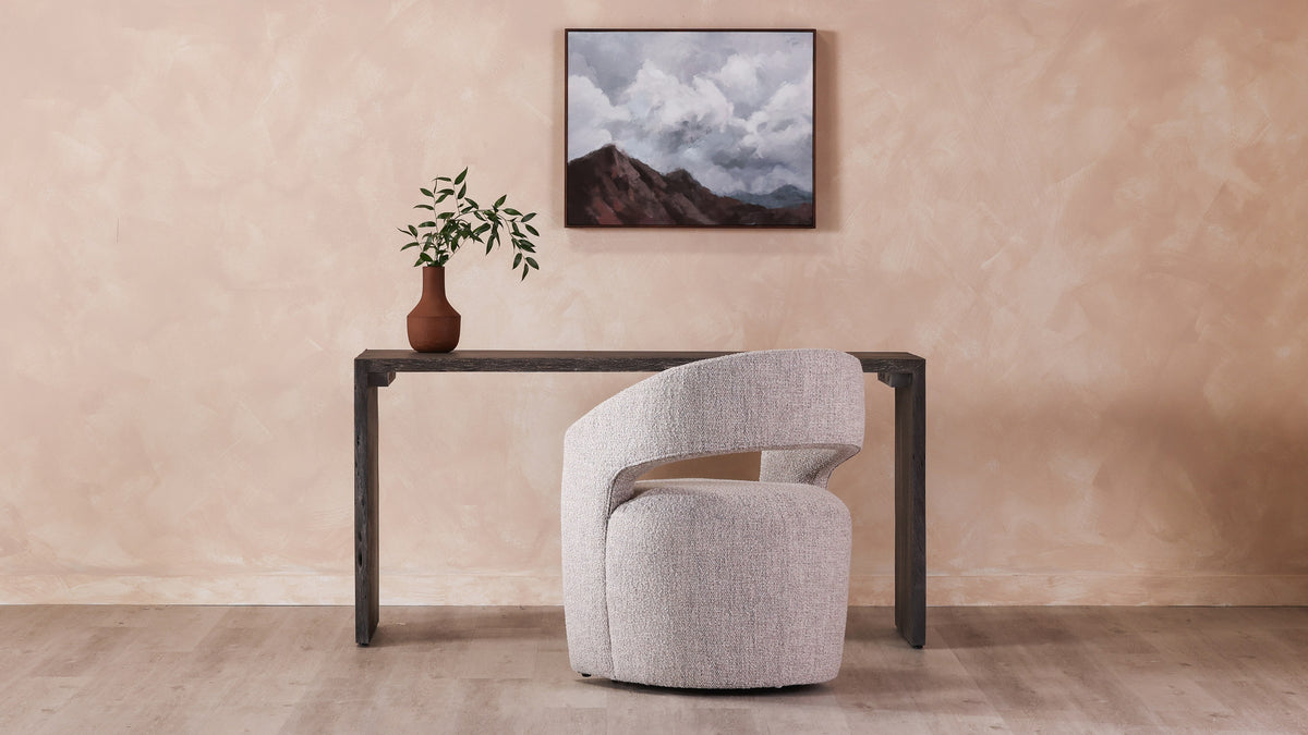 A single Moe's Home Collection Barrow rolling dining chair in gray storm boucle in front of a dark console table, showing the barrel back, the open gap under the arm and the boucle weave