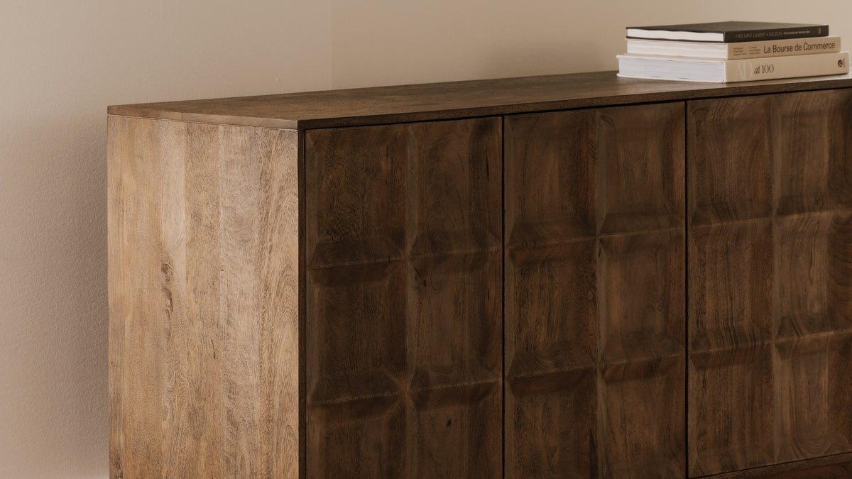 Close view of the Moe's Home Collection Bowen sideboard, showing the depth of its squared door panels in matte sandblast brown mango wood and a stack of books resting on the top