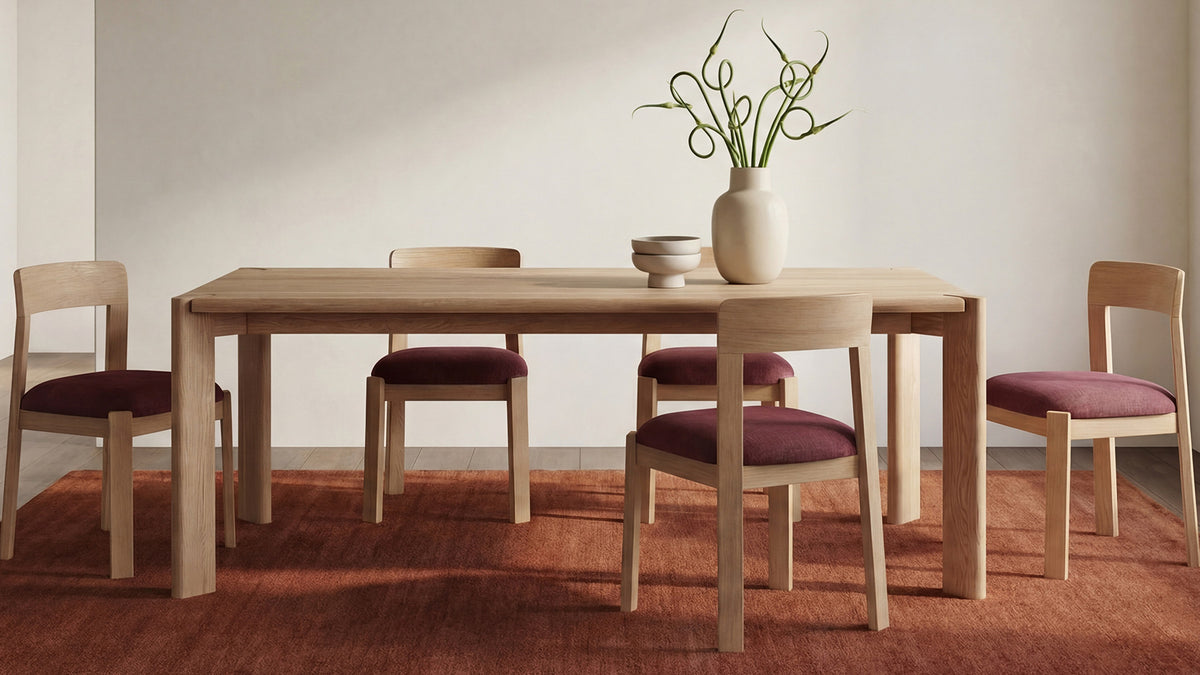 Daifuku dining table in brushed natural oak on a terracotta rug, surrounded by four pale oak chairs with burgundy upholstered seats, a ceramic vase and two small footed bowls on the top