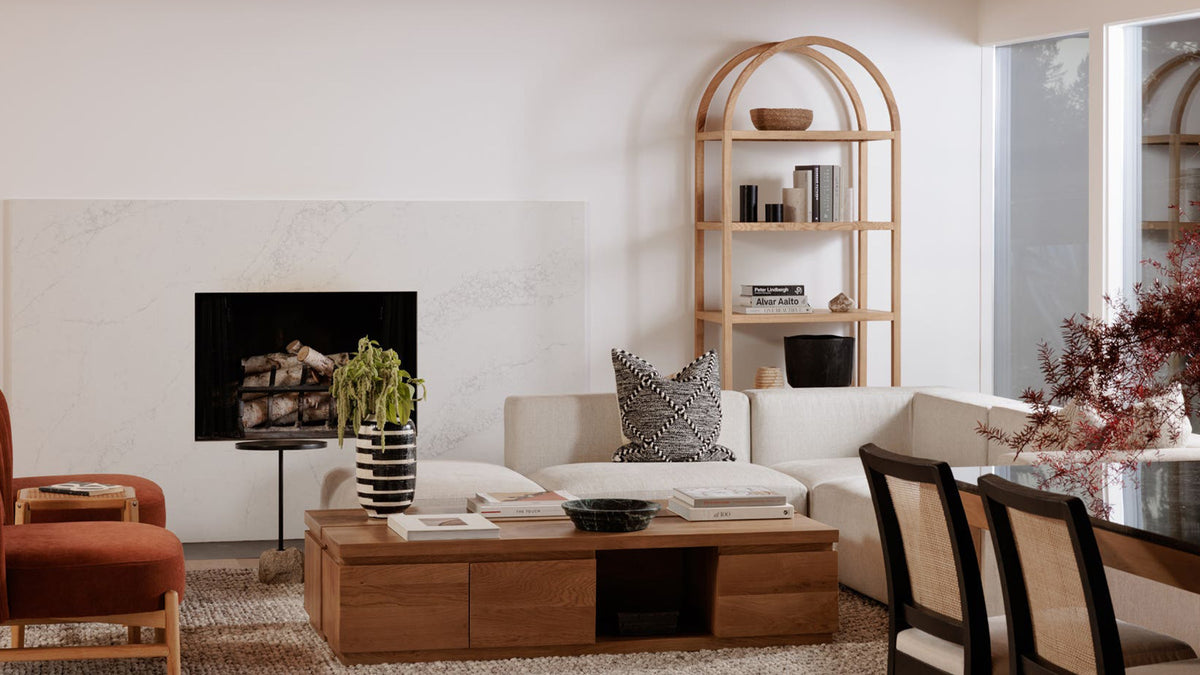 Moe's Home Collection Eero bookcase in natural oak, an arched open frame at the end of a living room, beside a fireplace and a pale sofa