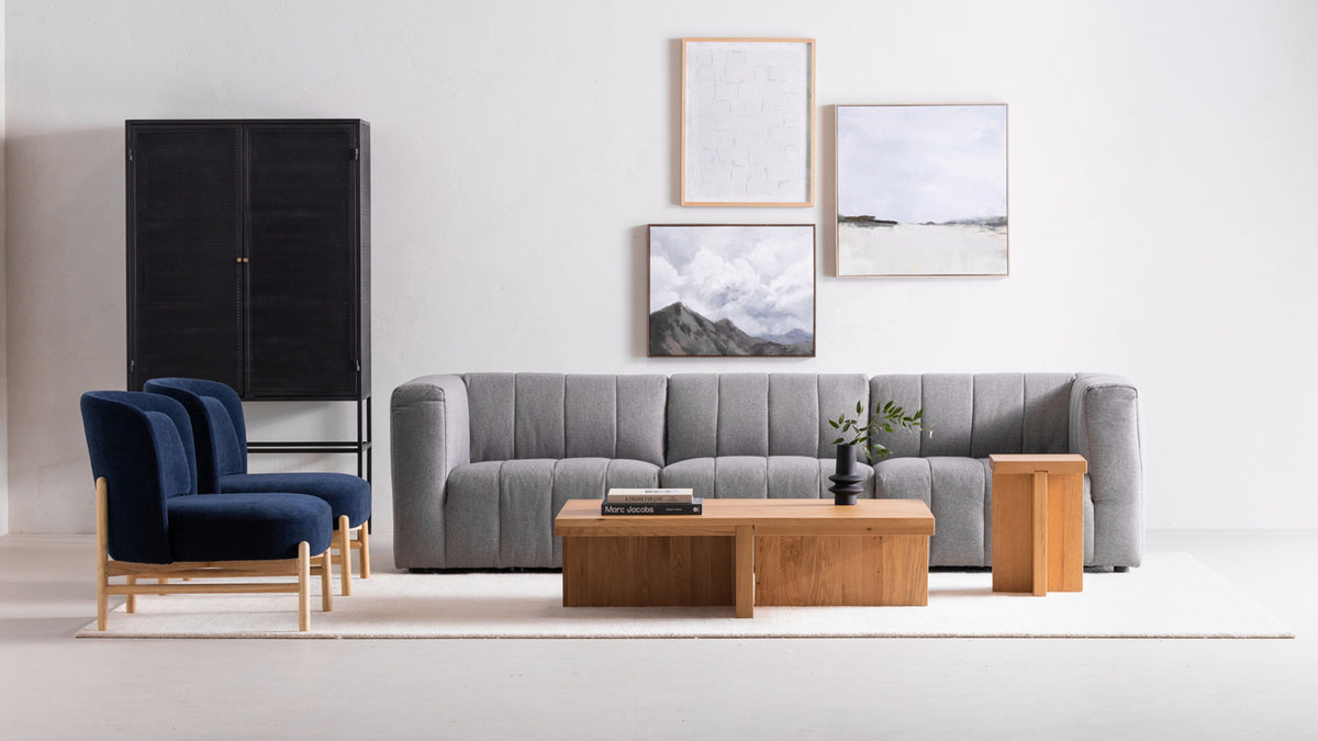 Moe's Home Collection Folke rectangular coffee table in solid oak with a Natural finish, pale and open-grained, before a grey channel-tufted sofa in a bright white room