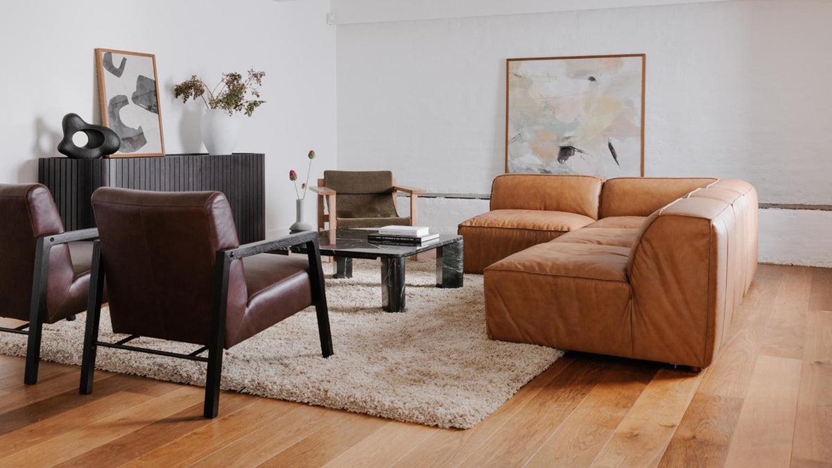 Form corner chair in Sonoran tan leather on an oak floor, seen from across the room at the end of a low modular run