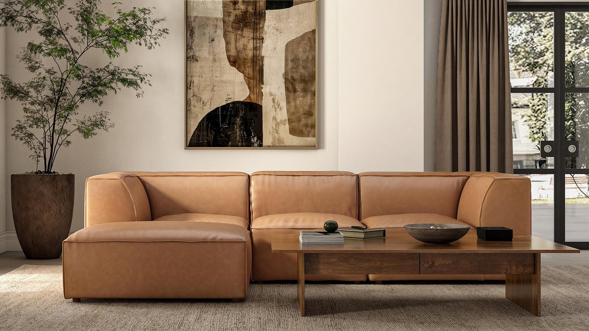 Form ottoman in Sonoran tan top-grain leather pulled up to a Form sectional along a living room wall beneath a large abstract canvas