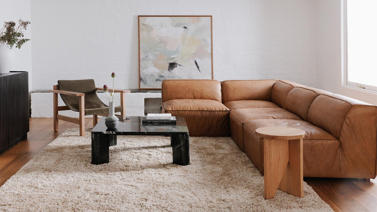 Form slipper chair in Sonoran tan leather in a white-walled room, seated in the run that leads into an L-shaped turn