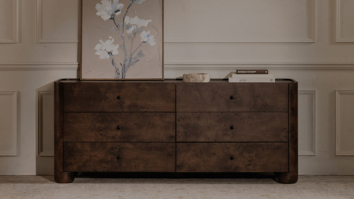 Moe's Home Collection Gibson dresser in natural oak seen at an angle in a bedroom, its leg panel running into the frame