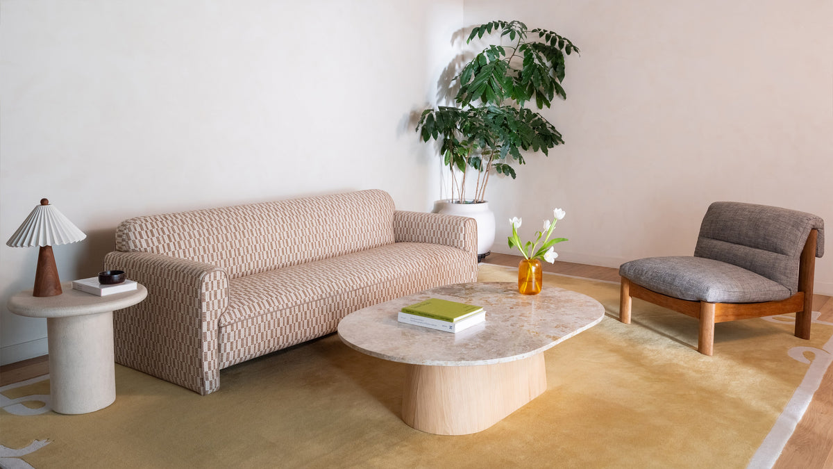 Moe's Home Collection Leo sofa in Chartreuse seen at an angle in a corner of a living room, between a stone side table with a pleated lamp and a gray sling chair, with a stone coffee table on an ochre rug