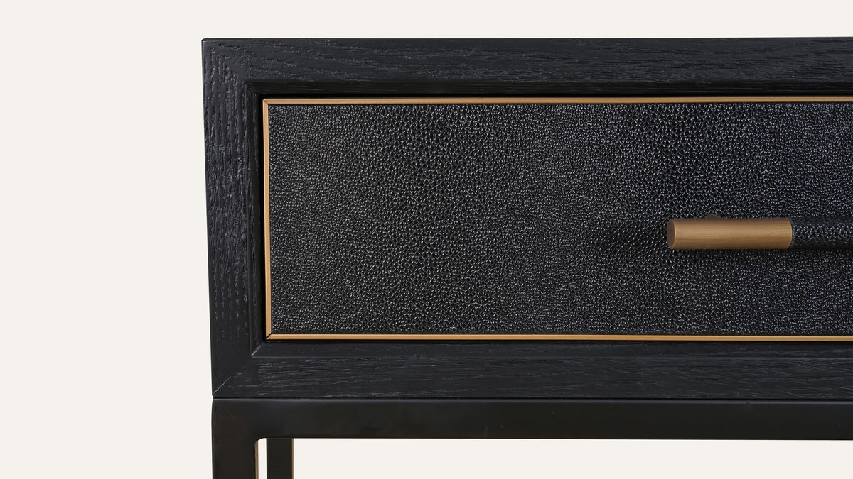 Close detail of the Mako console table's textured black drawer front, its brass bar pull and the brass line inset around the drawer