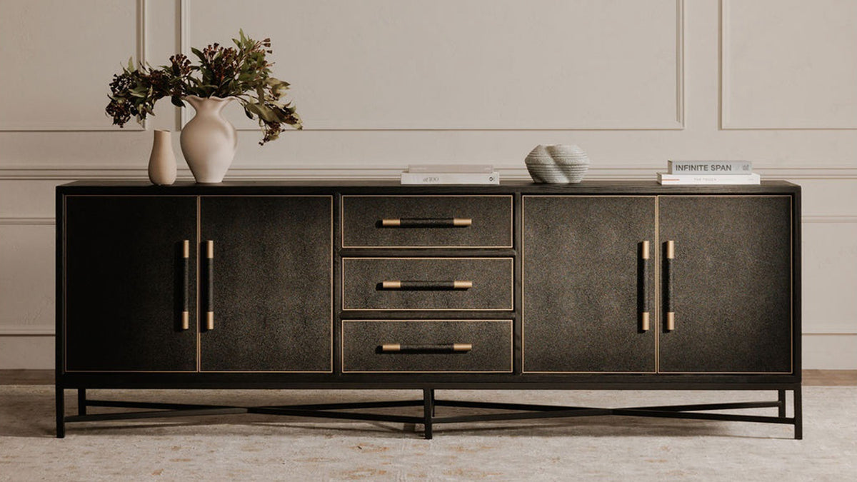 The larger Moe's Home Collection Mako sideboard in black, its long front spanning a panelled wall on a black metal base, with vases and books arranged across the top
