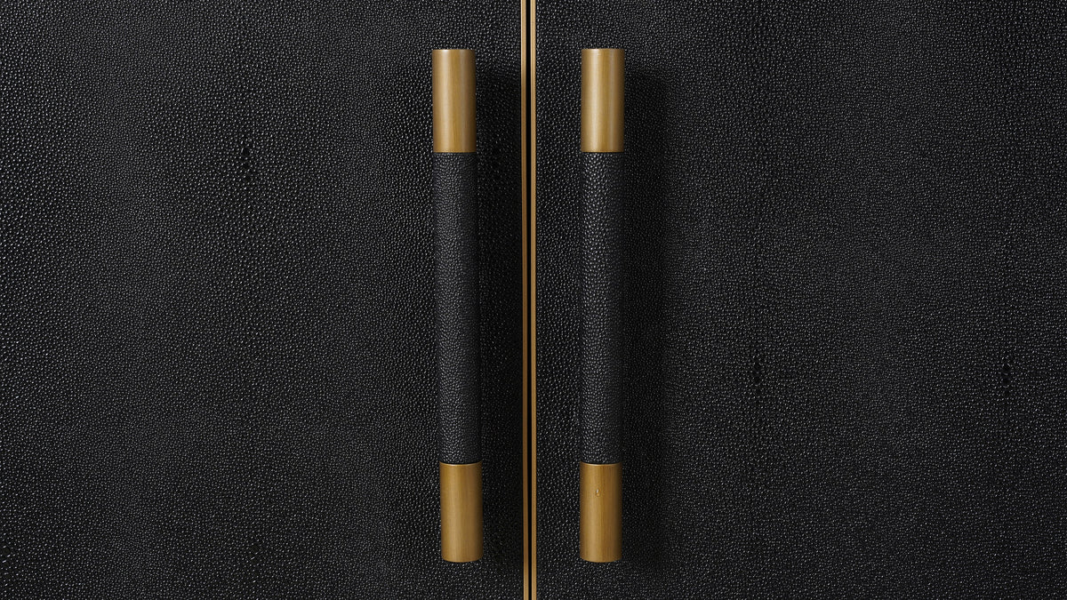 Close view of the Moe's Home Collection Mako sideboard doors, showing the fine pebbled shagreen texture of the black surface and the brass caps at each end of the pulls