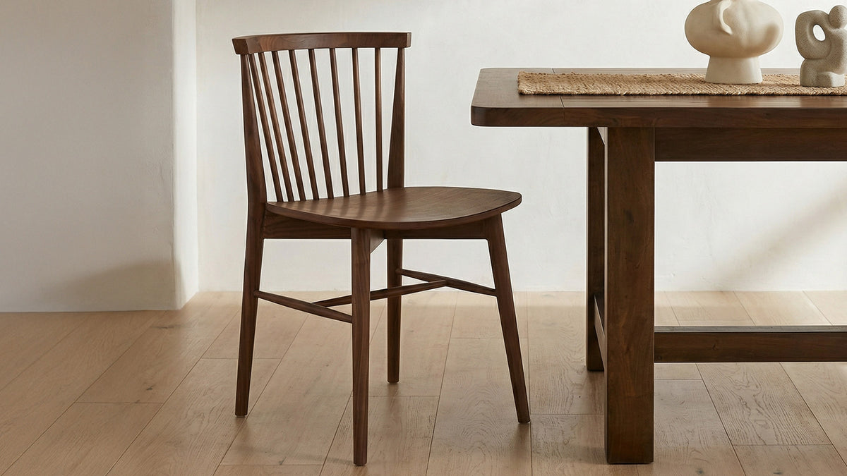 A single Moe's Home Collection Marley dining chair in solid walnut beside a walnut dining table on a light oak floor, its spindle back and shaped seat seen from three quarters