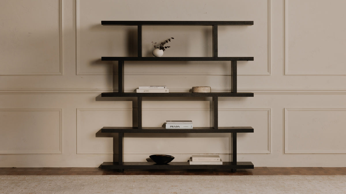Moe's Home Collection Miri Large bookshelf in black, five stepped planks against a panelled wall, with books and a dried stem