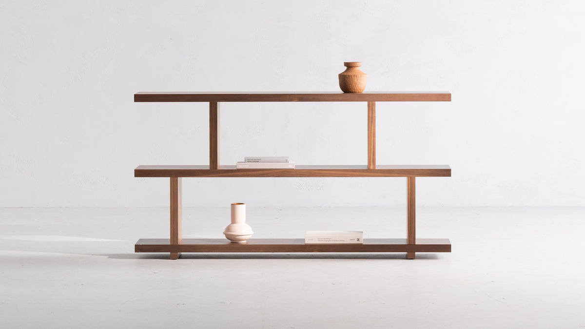 Moe's Home Collection Miri Small bookshelf in walnut, three planks stepping across two slim uprights, a rounded vessel on the top shelf
