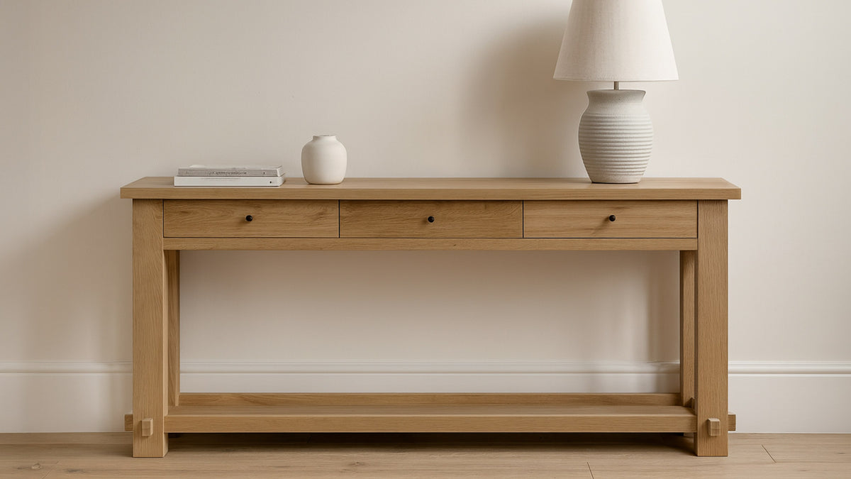 Moe's Home Collection Morey console table in natural oak, styled with a ribbed ceramic lamp, a small vase and a stack of books against a plain wall