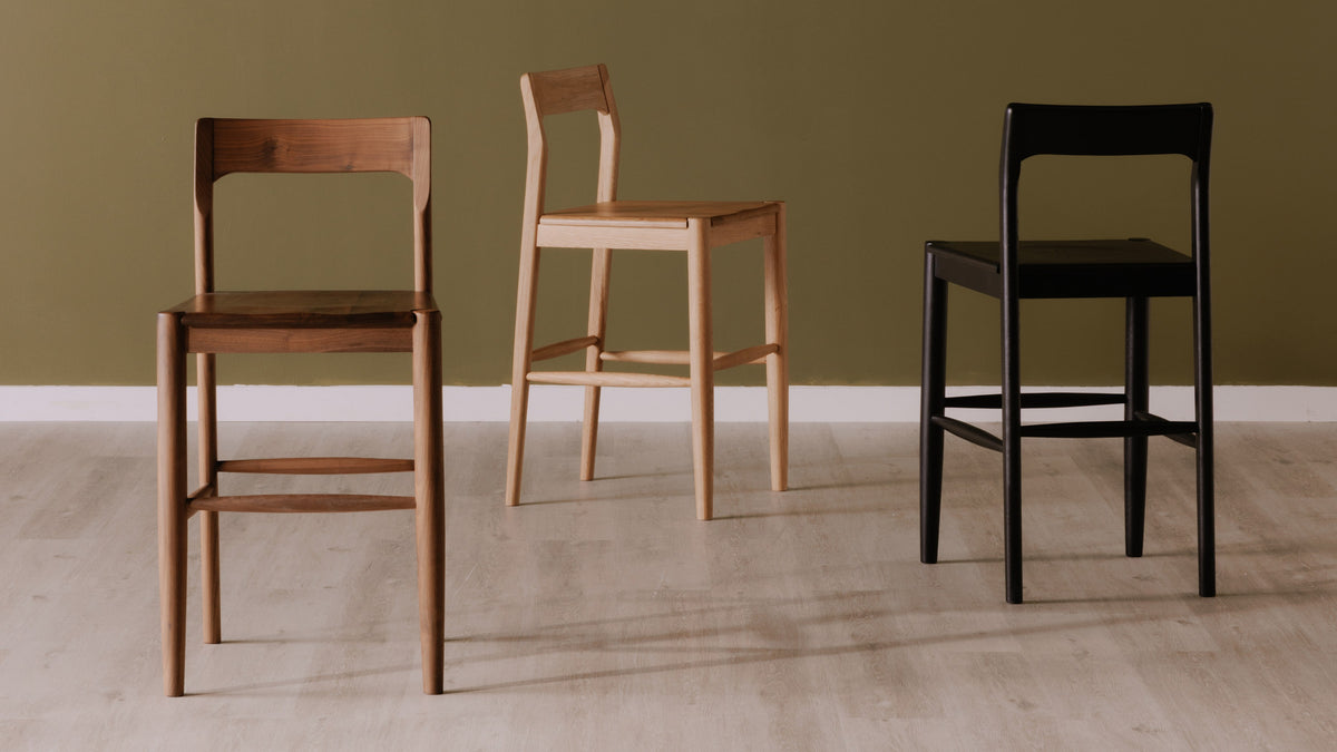 The Owing Counter Stool by Moe's Home Collection, solid walnut or solid oak with a curved open back, in a room setting