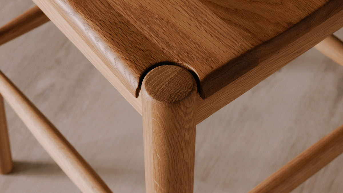 The Owing Counter Stool by Moe's Home Collection, solid walnut or solid oak with a curved open back, in a room setting