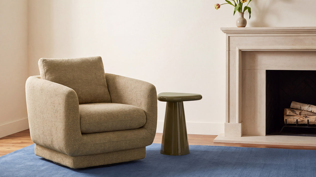 Rodi Side Table in Dark Green beside a lounge chair near a fireplace