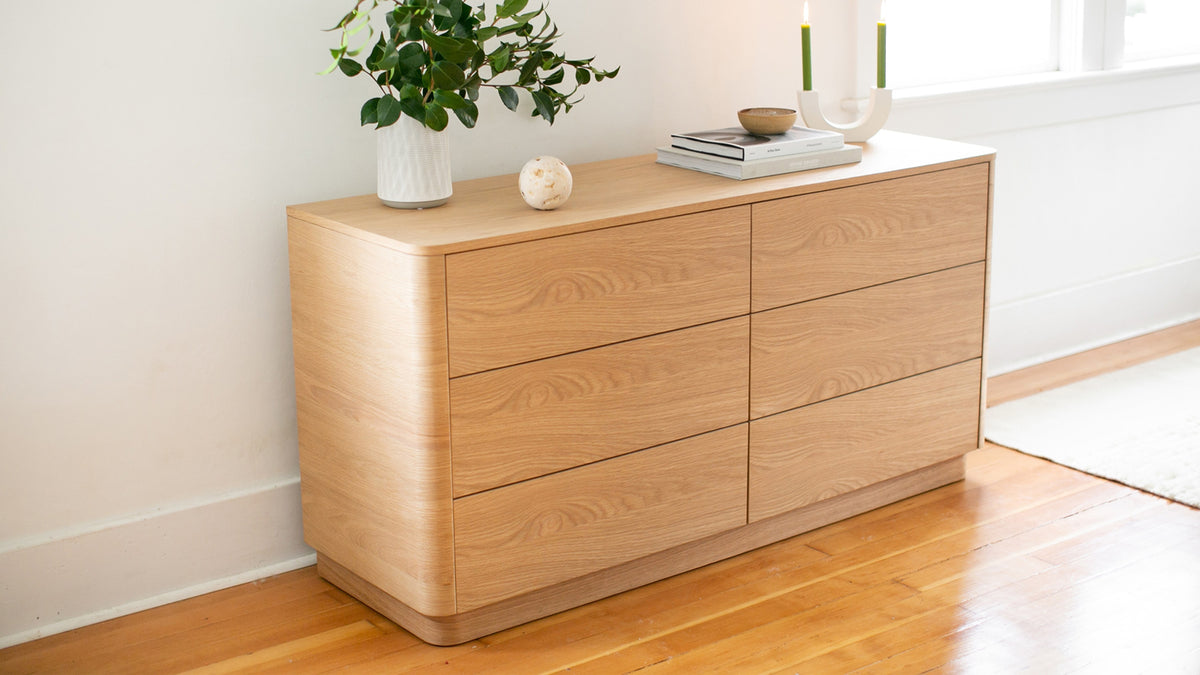 Moe's Home Collection Round Off dresser in light oak in a bedroom, its six drawers and softened corners below a wall of framed art