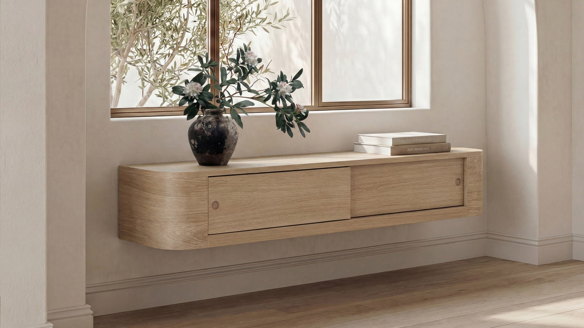 Moe's Home Collection Round Off floating console table in natural oak, wall mounted beneath a window and styled with olive branches in a dark ceramic vase and a small stack of books