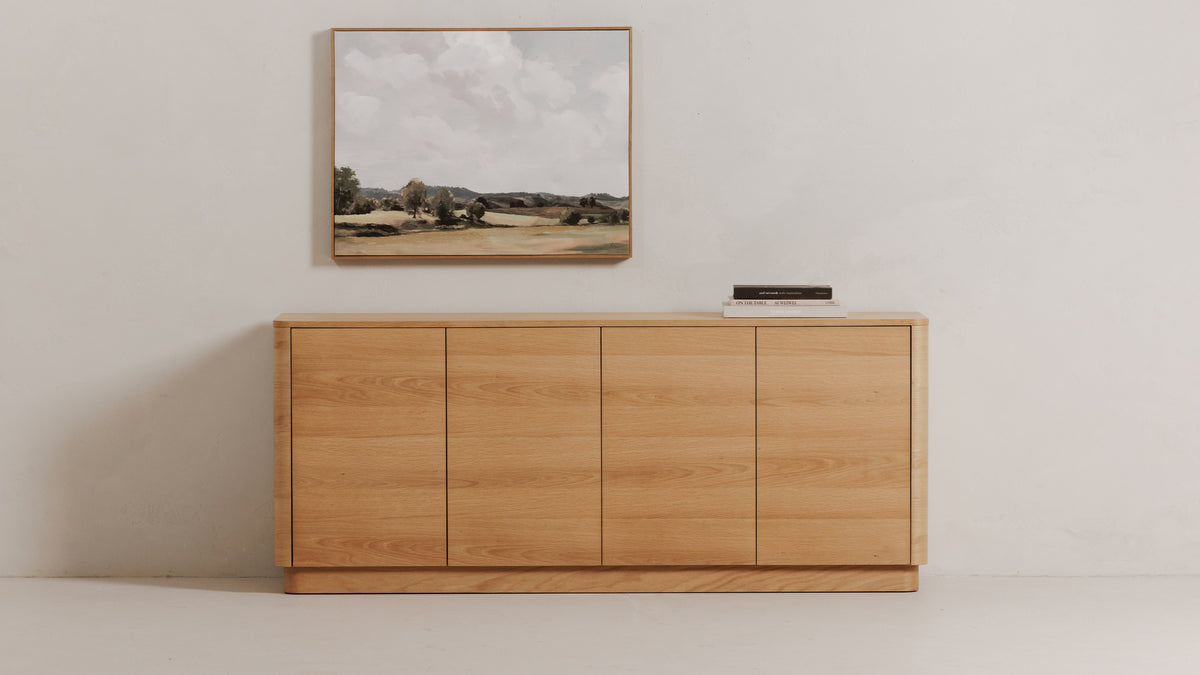 Moe's Home Collection Round Off sideboard in natural oak against a pale wall, its rounded corners and four seamless doors below a framed landscape painting