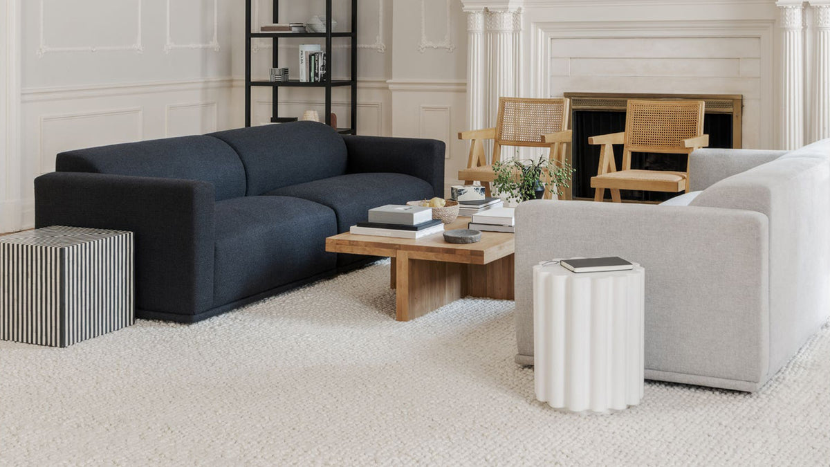 The Terning side table used as a bedside table beside a dark velvet bed, its black and white striped surface holding a book and a dark ceramic vase