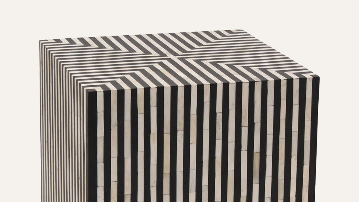 The Terning side table at the open end of a navy sofa in a panelled room, the only patterned object in an otherwise plain space